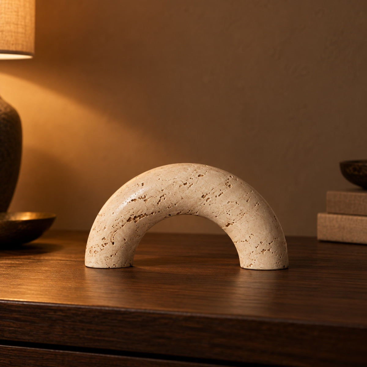 Travertine Look Arch Ornament close up on a walnut console