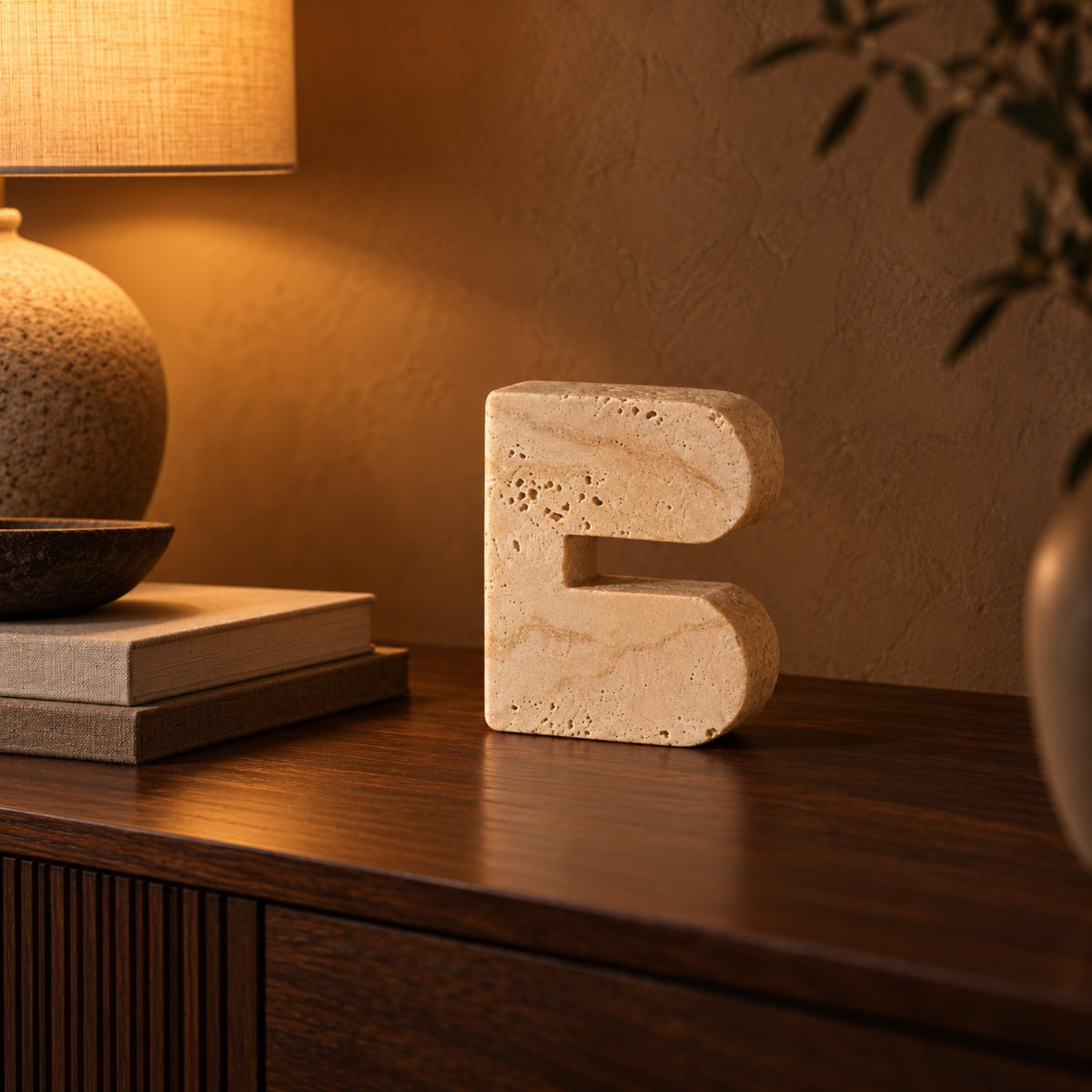 Travertine look cave arch sculpture styled beside a lamp and books