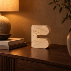 Travertine look cave arch sculpture styled beside a lamp and books