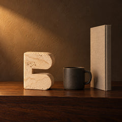 Cave Arch Travertine Look Sculpture beside a coffee mug and a hardcover book, showing its 16 cm height