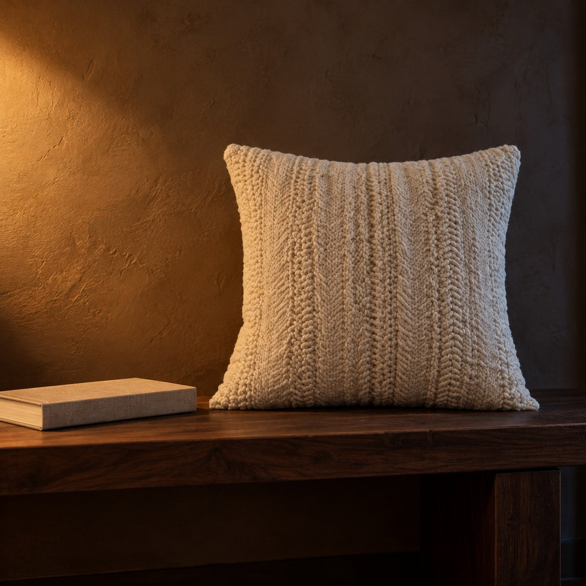 Ivory woven cushion next to a hardcover book for size