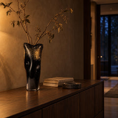 Noir Gilt black and gold glass vase with dried branches on a walnut console