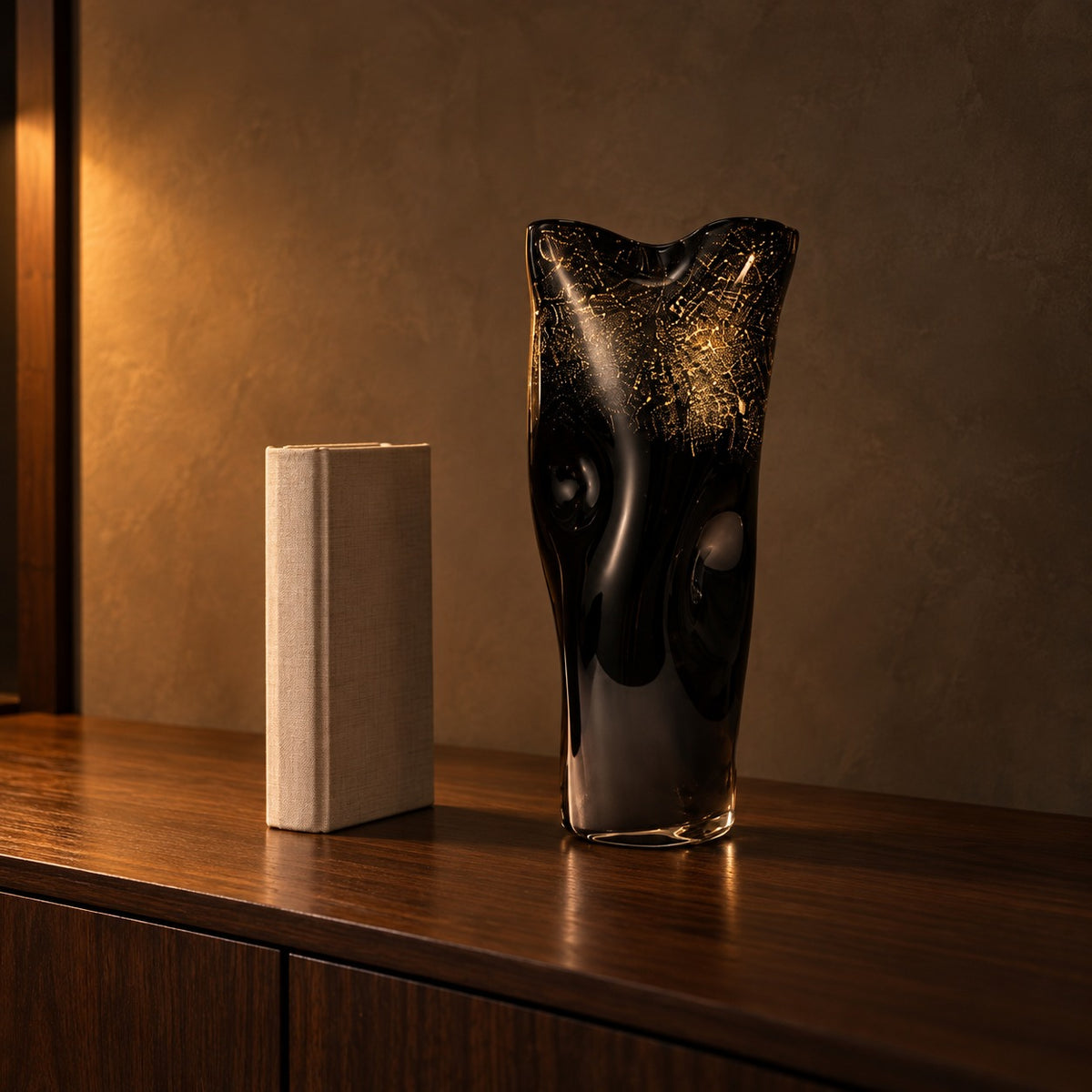 Noir Gilt black and gold glass vase next to a hardcover book for size
