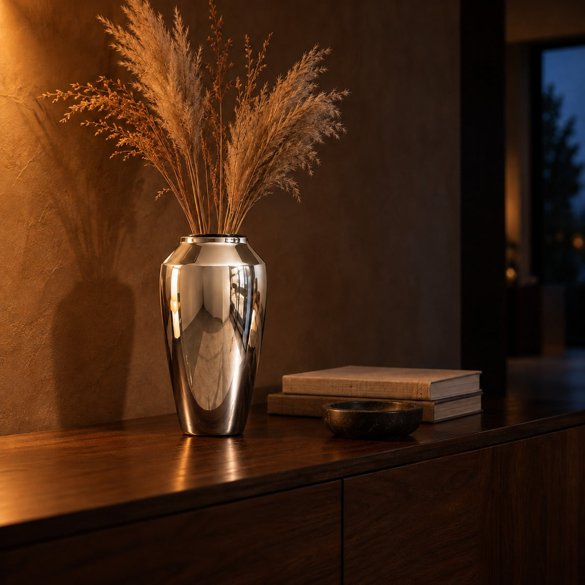 Silver mirror ceramic vase with dried grasses on a walnut console
