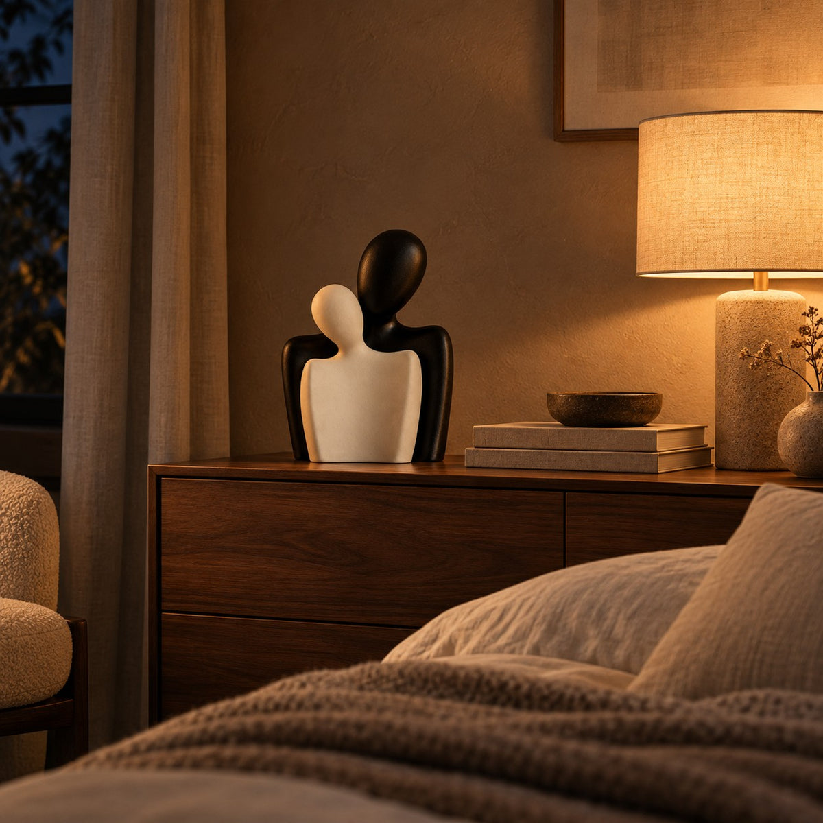 Embrace bust sculptures on a walnut bedroom sideboard at night
