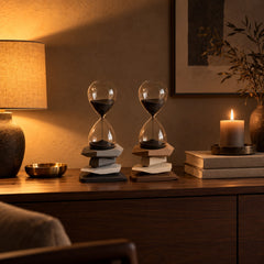 Two Cairn Hourglass Timers styled on a walnut console beside a warm lamp