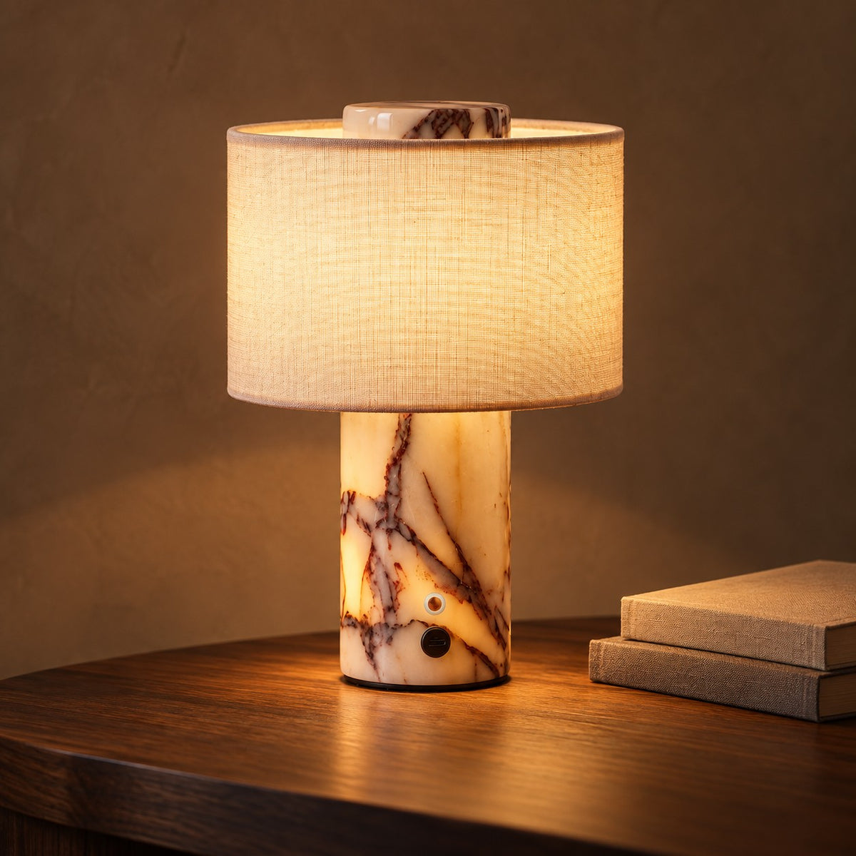 Marble Glow table lamp with cream linen shade glowing on a walnut table