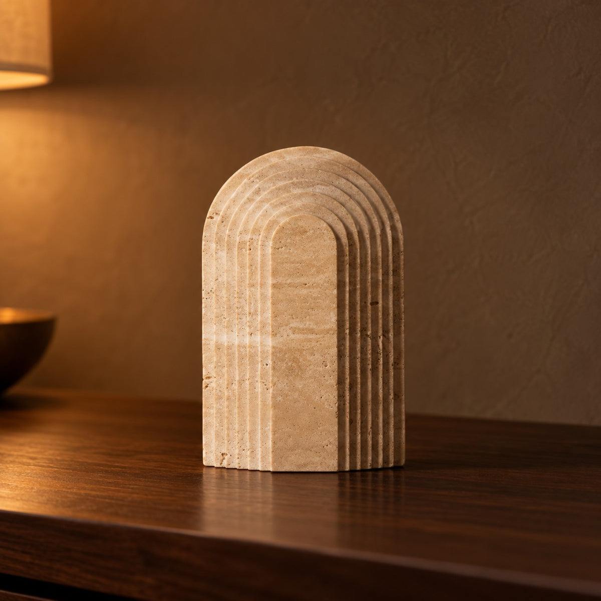Ridged Arch Travertine Ornament close up on a walnut console